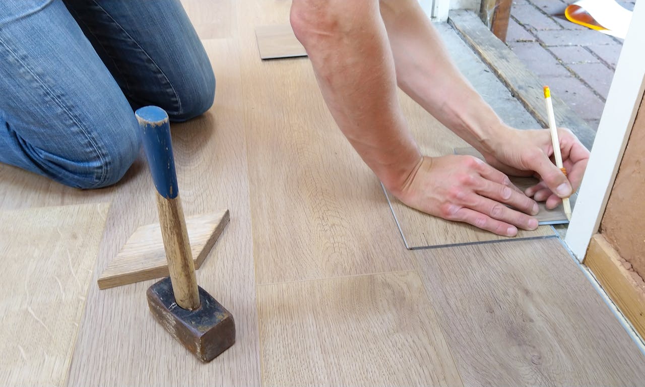 my-steps A craftsman carefully measures and marks wooden floor panels for precise installation.