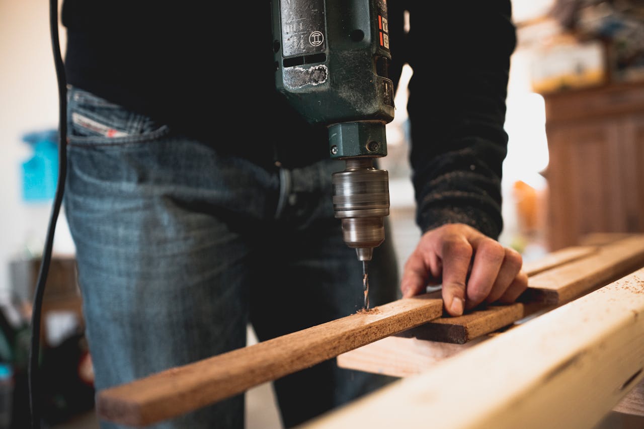 service-01 Close-up of a person using an electric drill on a wooden plank, showcasing detailed woodworking skills.