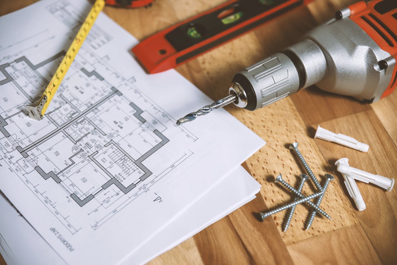 why-choose-me Close-up of construction blueprint with tools like drill and screws on a wooden table.